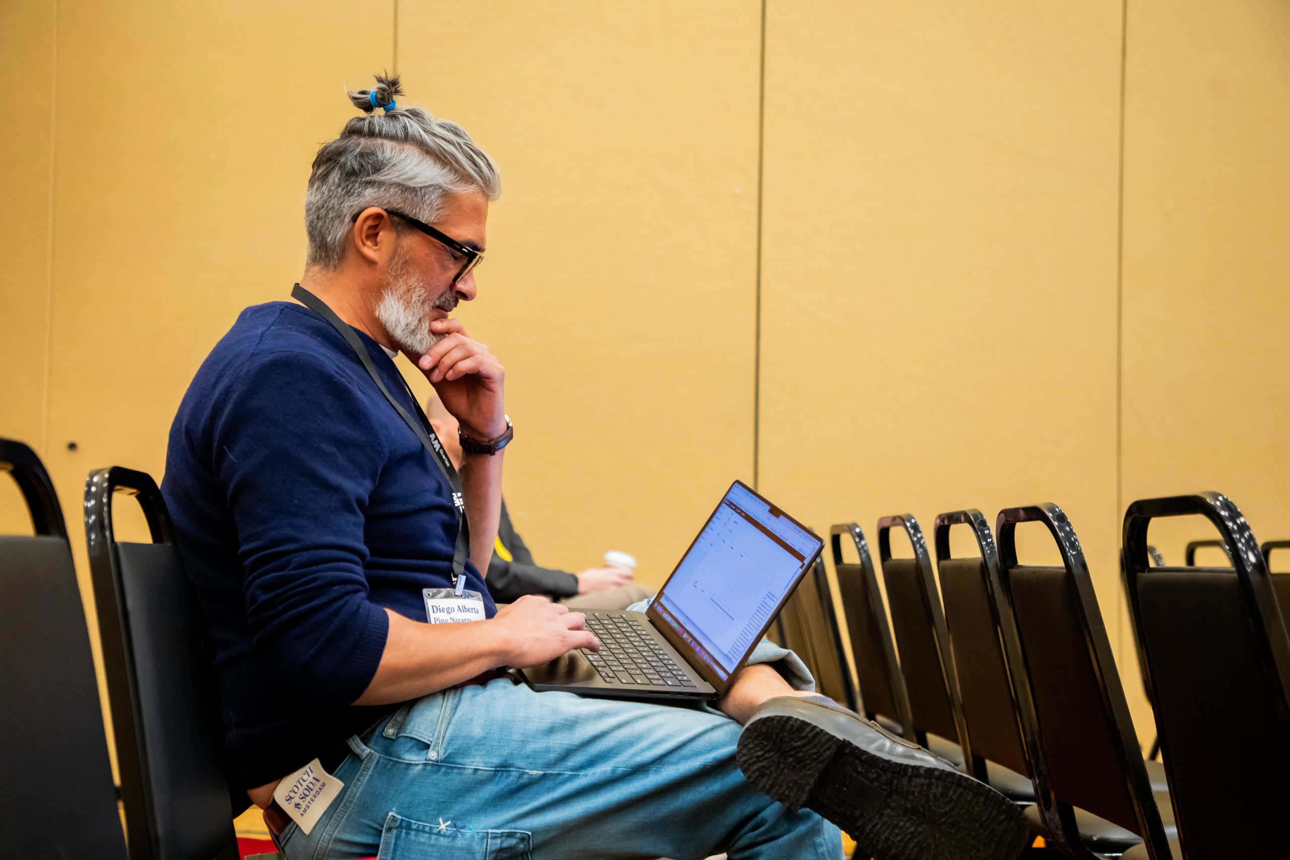 Person seated with a laptop on their lap.