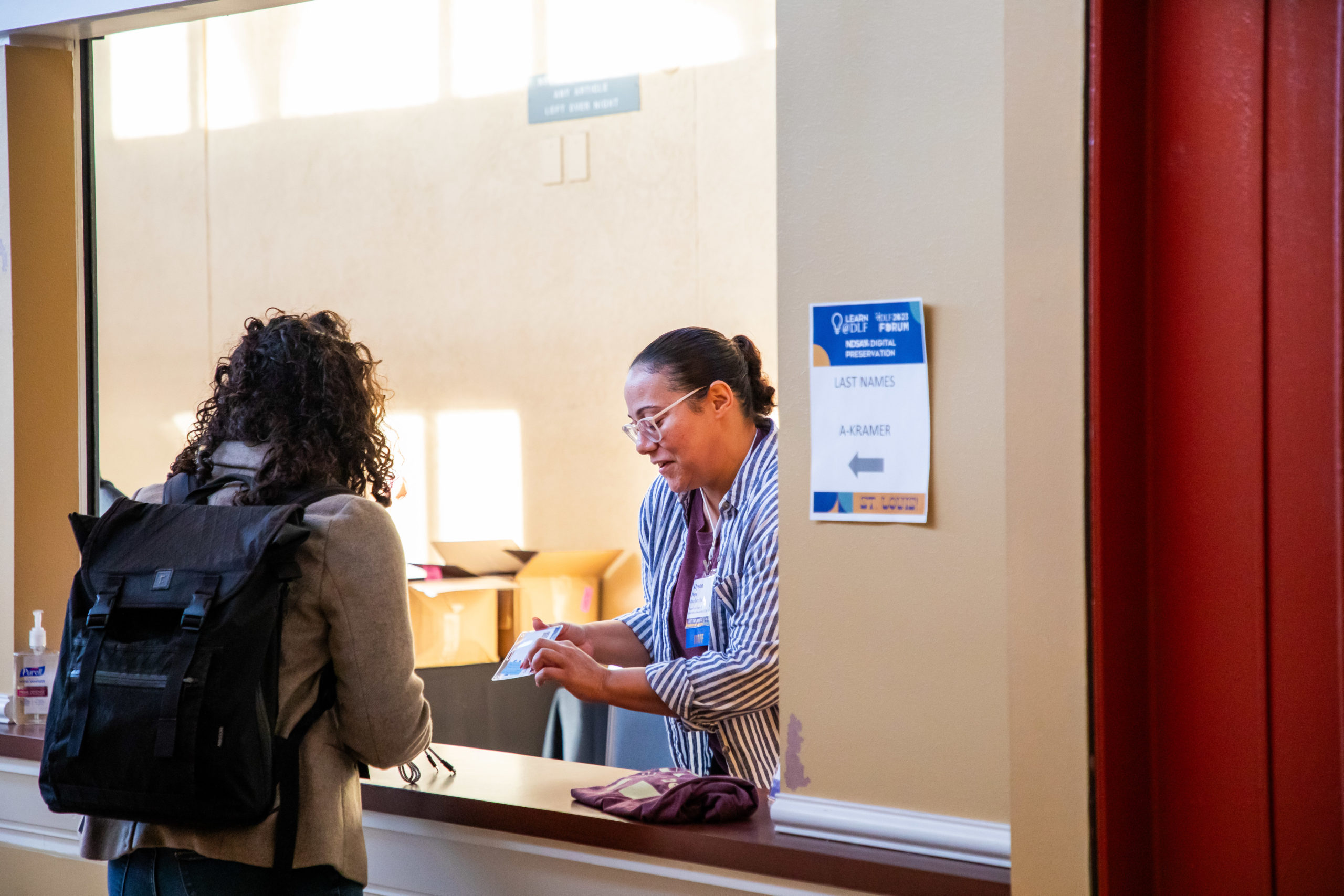 Person giving a conference badge to attendee.